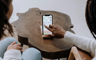 Zwei Kinder von hinten tippen auf das TikTok-Symbol auf dem Handy vor ihnen