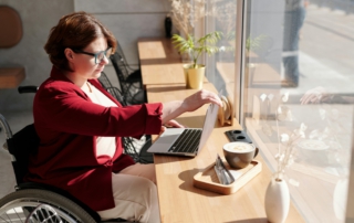 Frau im Rollstuhl arbeitet am Laptop