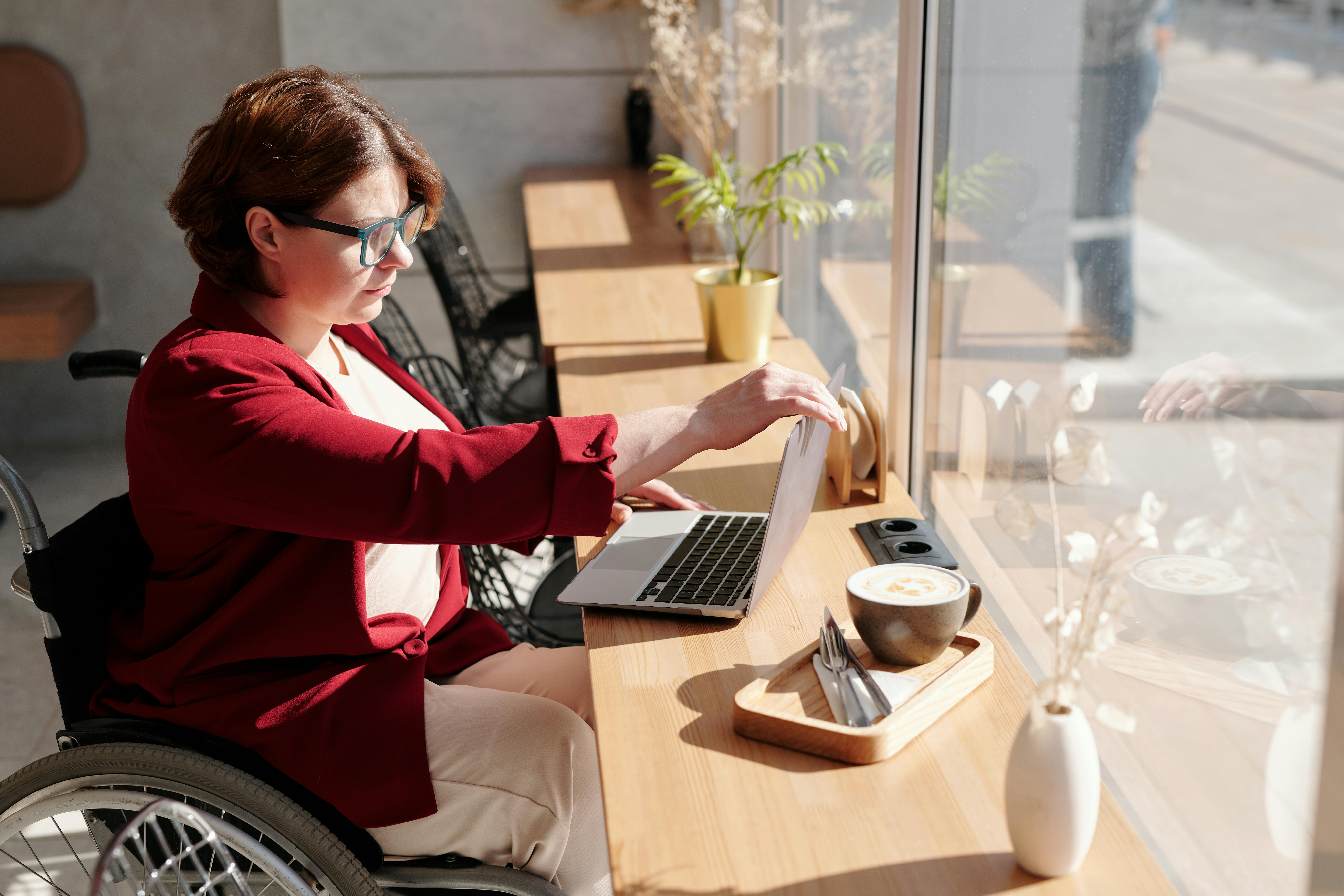 Frau im Rollstuhl arbeitet am Laptop